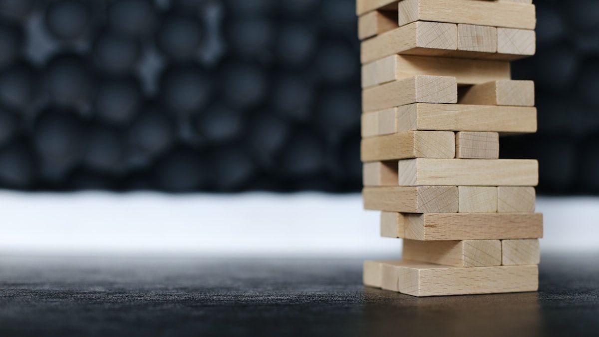 黒い机に置かれた木製ブロックの山。崩れやすさに注意する場面のイメージ
