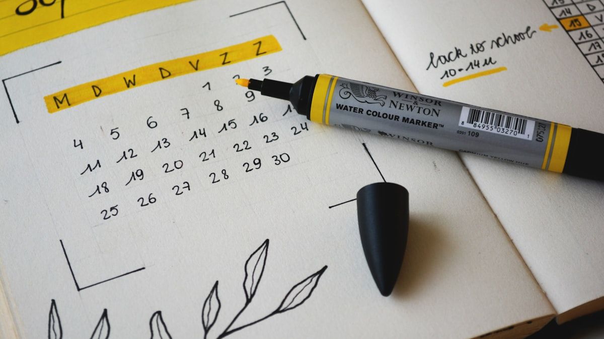 机に開かれた予定表と眼鏡、ペン。社内の時間を書き出す場面のイメージ
