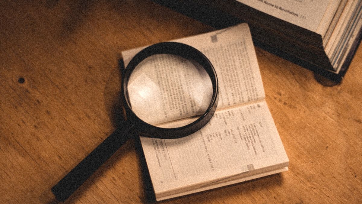 開いた本の上に虫眼鏡を置き、言葉をひとつずつ拾う様子のイメージ