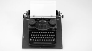白い背景に置かれたタイプライターと差し込まれた白紙の用紙