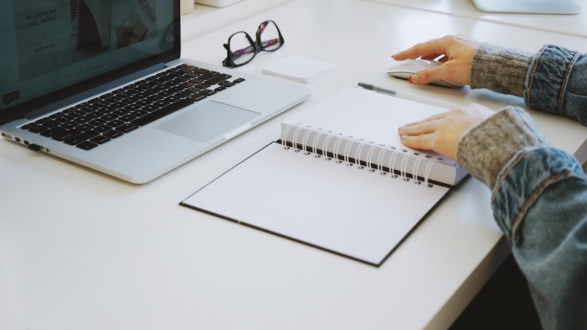 コンテンツSEOで外注できる工程をノートに書き出しながらノートパソコンで作業している手元