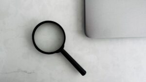 ディスクリプションの文字数を調べる場面を表す机の上の虫眼鏡とノートパソコン