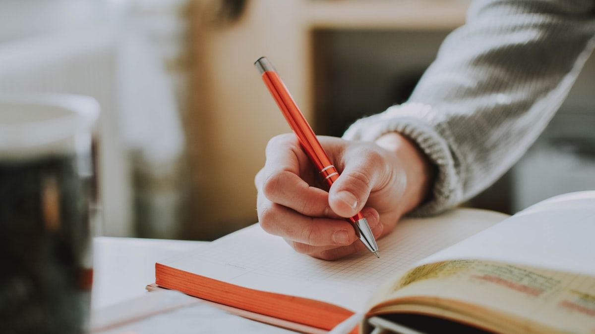 赤ペンを持って紙面に書き込む手元。原稿を読んで判断する場面のイメージ