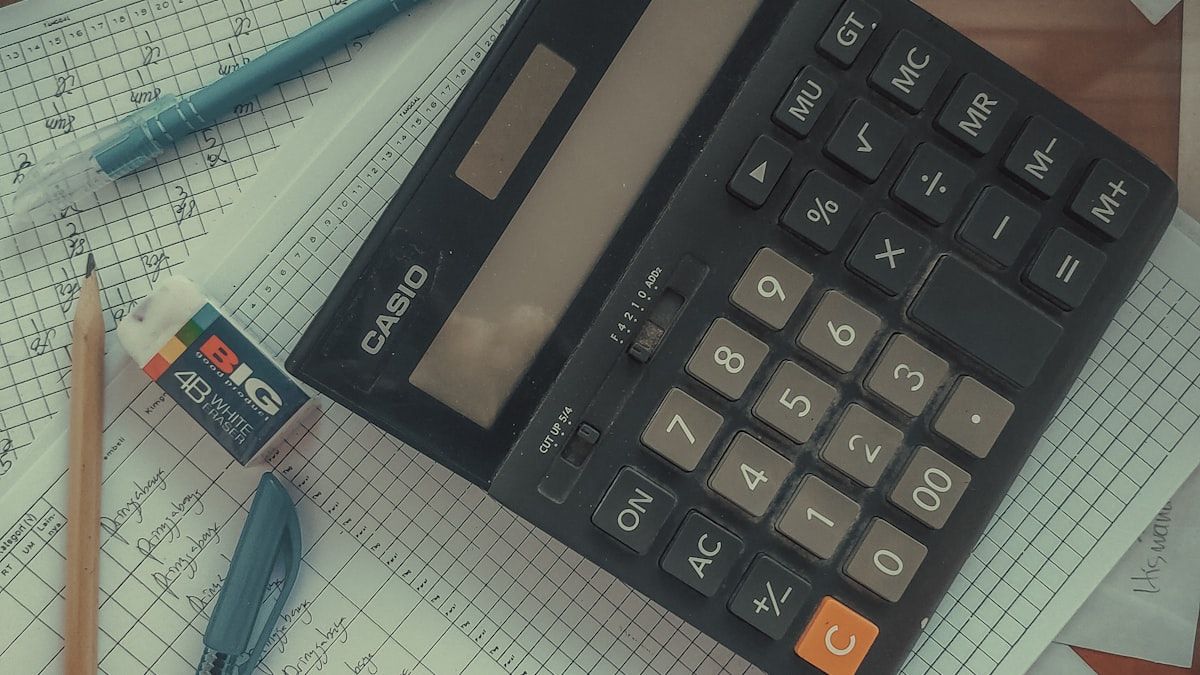 記事数の目安を調べる場面。書類の束の上に置かれた電卓