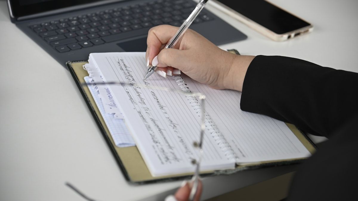 他社事例から得た確認事項を自社のノートに書き出している手元